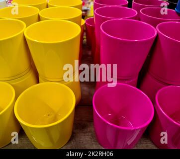 Une pile de pots de fleurs décoratifs jaunes et roses. Banque D'Images