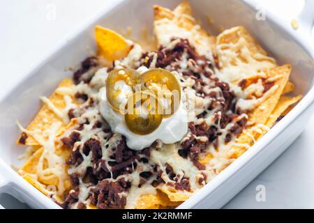 nachos avec viande hachée de bœuf et fromage servis avec de la crème fouettée et des jalapenos Banque D'Images