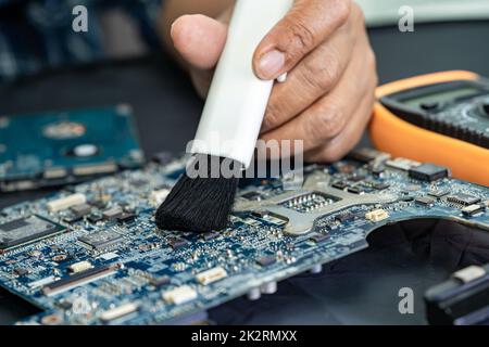 Le technicien utilise une brosse et une boule de soufflerie d'air pour nettoyer la poussière de l'ordinateur de la carte de circuit imprimé. Réparer la technologie de mise à niveau et de maintenance. Banque D'Images