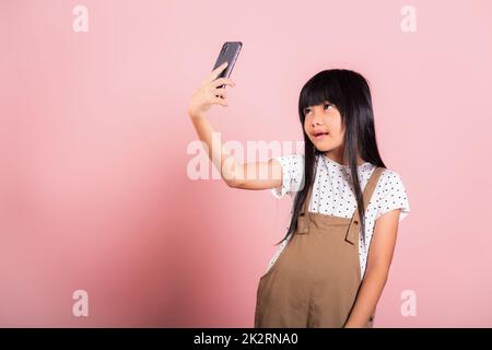 Enfant asiatique 10 ans profiter de l'utilisation du téléphone mobile prendre selfie Banque D'Images