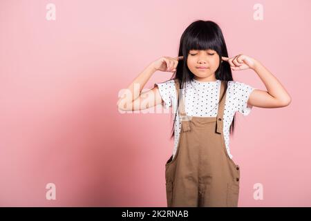 Petit enfant asiatique de 10 ans Fermez ses oreilles avec les doigts et les yeux Banque D'Images