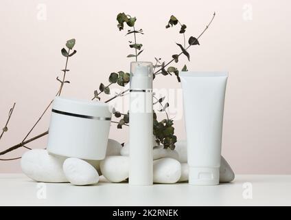 Pot, bouteille et tubes en plastique blanc vides pour cosmétiques sur fond beige. Banque D'Images