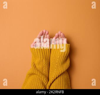 deux mains de femme replient la paume sur la paume sur un fond orange, vue du dessus Banque D'Images