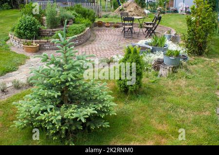 jardin rustique - épicéa, plantes dans une baignoire en étain, spirale d'herbes, chaises et table Banque D'Images