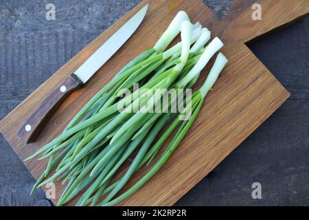 Vue de dessus du bouquet d'oignons de printemps prêt à couper sur la planche à découper Banque D'Images