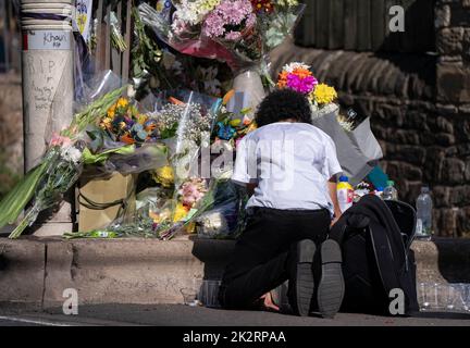 Un élève voit des hommages floraux sur la scène de Woodhouse Hill, à Huddersfield, où Khayri McLean, jeune garçon de 15 ans, a été mortellement poignardé devant ses portes. Date de la photo: Vendredi 23 septembre 2022. Banque D'Images