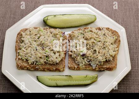 Deux sandwichs à salade de poulet à surface ouverte sur une assiette avec pickles à l'aneth Banque D'Images