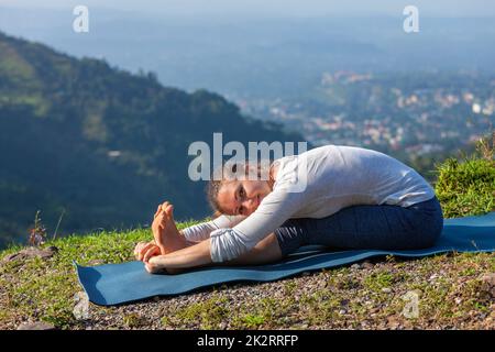 Woman doing yoga asana Paschimottanasana flexion avant Banque D'Images