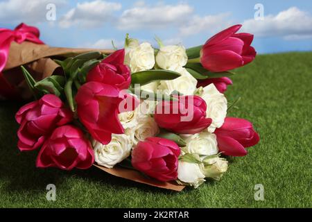 Bouquet de tulipes roses et de roses blanches sur l'herbe verte Banque D'Images