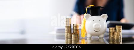 Close-up of Piggy Bank Wearing Graduation Hat et pièces empilées Banque D'Images