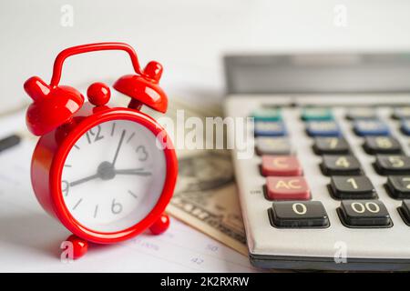 Alarm clock with coins on US dollar banknotes, finance installment loan time. Stock Photo