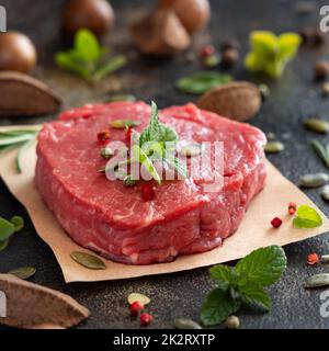 Steak de filet de bœuf cru aux herbes et aux épices sur une table sombre Banque D'Images