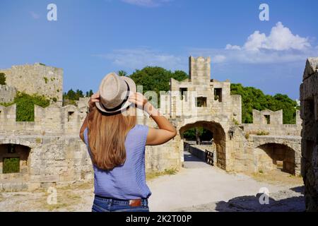 Vacances à Rhodes, Grèce. Vue arrière de la jeune fille de voyageur appréciant la vue de la porte de Saint Paul dans la ville de Rhodes fortifications, Grèce. Jeune femme touriste en visite dans le sud de l'Europe. Banque D'Images