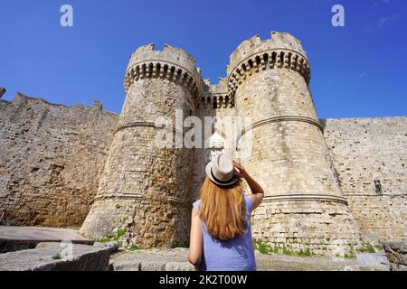 Tourisme en Grèce. Vue arrière de la jeune fille touristique qui descend à l'entrée principale de la porte Marine à Rhodes depuis le port, Grèce. Patrimoine mondial de l'UNESCO. Banque D'Images