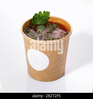 Cuisine nationale ukrainienne - borsch rouge avec légumes, viande et aneth. Soupe aigre dans une tasse en papier sur fond blanc. Banque D'Images