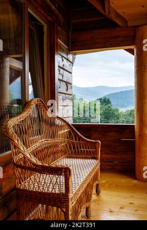 Terrasse avec banc en osier sur balcon en bois avec vue sur la montagne. Banque D'Images