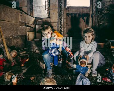 Jeunes enfants créepeux assis avec de vieilles poupées dans une grange Banque D'Images