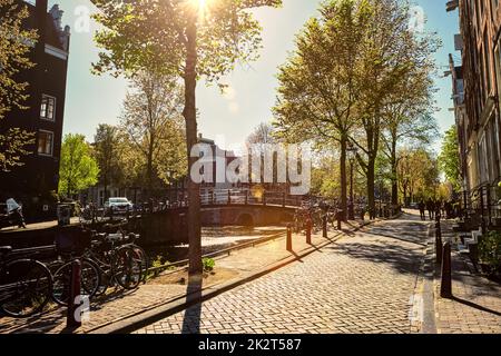 Rue d'Amsterdam avec canal et maisons anciennes et vélo au coucher du soleil. Amsterdam, pays-Bas Banque D'Images
