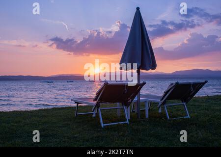 Chaises longues avec parasol sur le lac de garde Banque D'Images