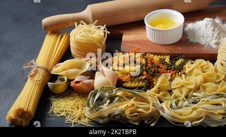 Assortiment de pâtes brutes. Différents types de macaroni, tagliatelle, farfalle, spaghetti, penne rigate . Coloré, rouge, vert, jaune, nouilles. Banque D'Images
