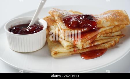 Crêpes françaises pour le petit déjeuner avec confiture de fraises. Pancakes ou crêpes de levure de blé doré dans une assiette blanche. Banque D'Images