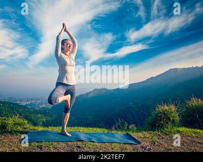 Woman doing yoga asana Vrikshasana posture de l'arbre dans les montagnes à l'extérieur Banque D'Images
