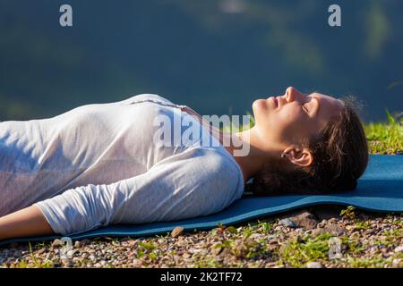 Femme se détend en yoga asana Savasana outdoors Banque D'Images