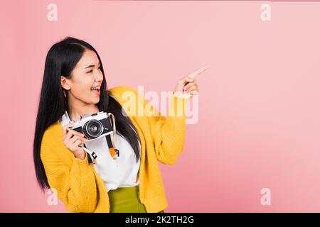 femme adolescente souriante tenant un appareil photo d'époque et un doigt pointé Banque D'Images