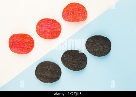 Chips de pommes de terre rouges et noires avec sel, piment. Mise en plan isométrique. Fond de puce sur fond blanc et bleu. Banque D'Images