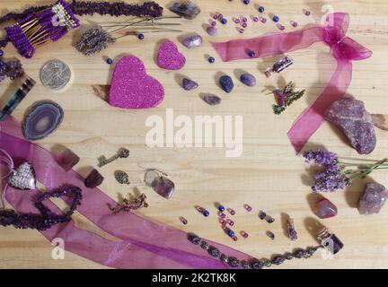 Bijoux violet et rose avec coeurs à paillettes et pierres améthystes sur fond en bois Banque D'Images