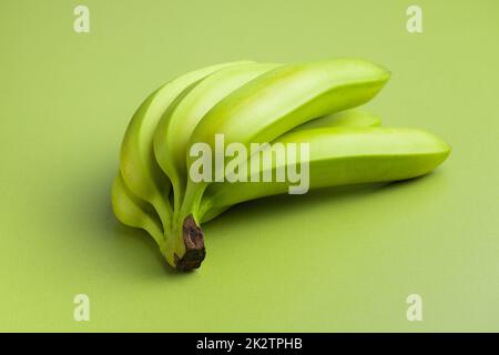 Bananes vertes non mûres sur table verte. Banque D'Images