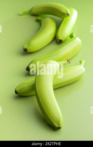 Bananes vertes non mûres sur table verte. Banque D'Images