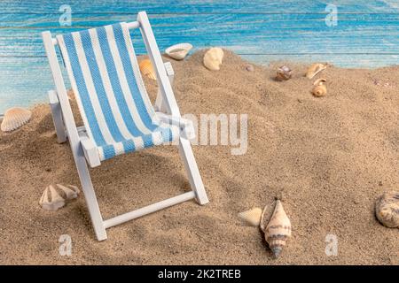 Chaise longue et coquillages sur le sable sur fond bleu Banque D'Images