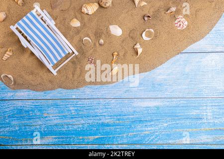 Chaise longue et coquillages sur le sable sur fond bleu Banque D'Images