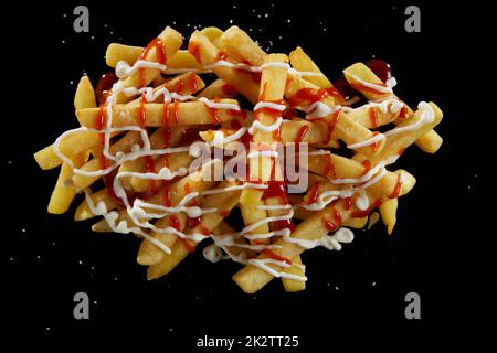 Frites délicieuses avec sauces et sel sur fond noir Banque D'Images