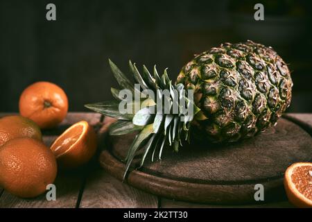 Ananas et oranges sur table en bois Banque D'Images
