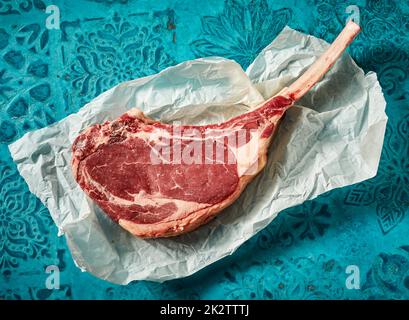 Steak cru sur du papier froissé sur une table à motifs Banque D'Images