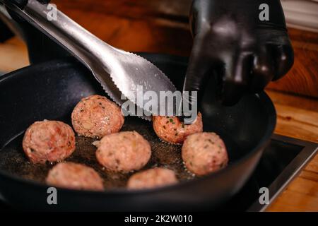 Gros plan faites frire des boulettes de viande sur une poêle chaude Banque D'Images