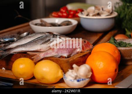 La dorade et les coquillages sur la table à côté des légumes et des fruits.Ingrédients pour préparer une délicieuse soupe.Cuisine fine. Banque D'Images