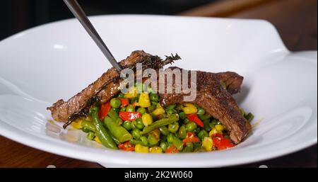 Assiette de viande de bœuf et de légumes.Haricots verts de maïs frits.Cuisine sur une assiette blanche au restaurant. Banque D'Images