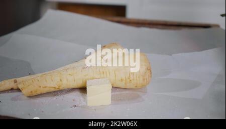 Assaisonner les racines de légumes comme le persil ou le panais en préparation pour la cuisson. Banque D'Images