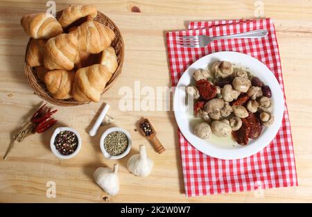 Champignons, tomates séchées au soleil, olives et câpres en huile d'olive sur table rustique Banque D'Images