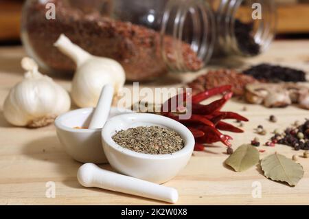 Herbes et épices sur table rustique avec jarres de riz rouge et brun en arrière-plan Banque D'Images