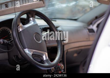 Gros plan du volant d'une voiture après un accident. Les airbags conducteur ne se sont pas déployés. Mise au point douce. Pare-brise cassé avec volant. Intérieur du véhicule. Tableau de bord et volant noirs. Banque D'Images