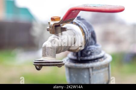 Robinet d'eau sur fond de nature. L'ouverture ou la fermeture d'un robinet pour économiser de l'eau indique un problème de pénurie d'eau. Fontaine rustique avec lumière du jour. Mise au point sélective avec arrière-plan flou. Banque D'Images