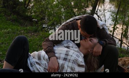 Beau couple relaxant dans la forêt par un beau jour, homme embrassant petite amie allongé dans ses genoux. Histoire d'amour du camping Banque D'Images