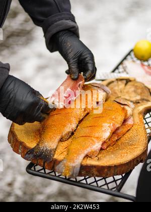 Grilleman prépare la truite au gril et enveloppe le bacon autour du poisson Banque D'Images