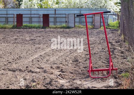 Pelle rouge sous forme de fourche dans le jardin. Pelle miracle, outil pratique. Cultivateur manuel. Le cultivateur est un outil efficace pour le travail du sol. Desserrage du lit. Outils agricoles durables. Banque D'Images