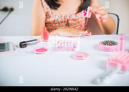 petite fille faisant le maquillage trempette brosse dans la bouteille pour peindre les ongles vernis à ongles rouge elle-même Banque D'Images