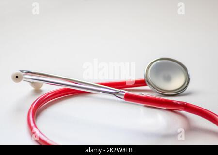 Stéthoscope rouge dans le bureau des médecins pour un examen cardio professionnel et un contrôle du pouls cardiaque sain par un cardiologue dans la salle de traitement clinique sur le bureau blanc comme équipement médical pour mesurer les params du corps Banque D'Images